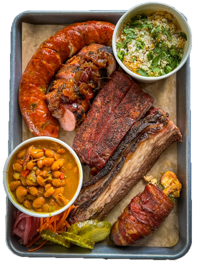 Barbecue platter from Hootenanny's BBQ in Brunswick, GA, featuring large smoked pork ribs, smoked sausage, and brisket, served with two bowls of baked beans topped with chopped herbs, and pickles, with shredded carrots and red onion as garnish.