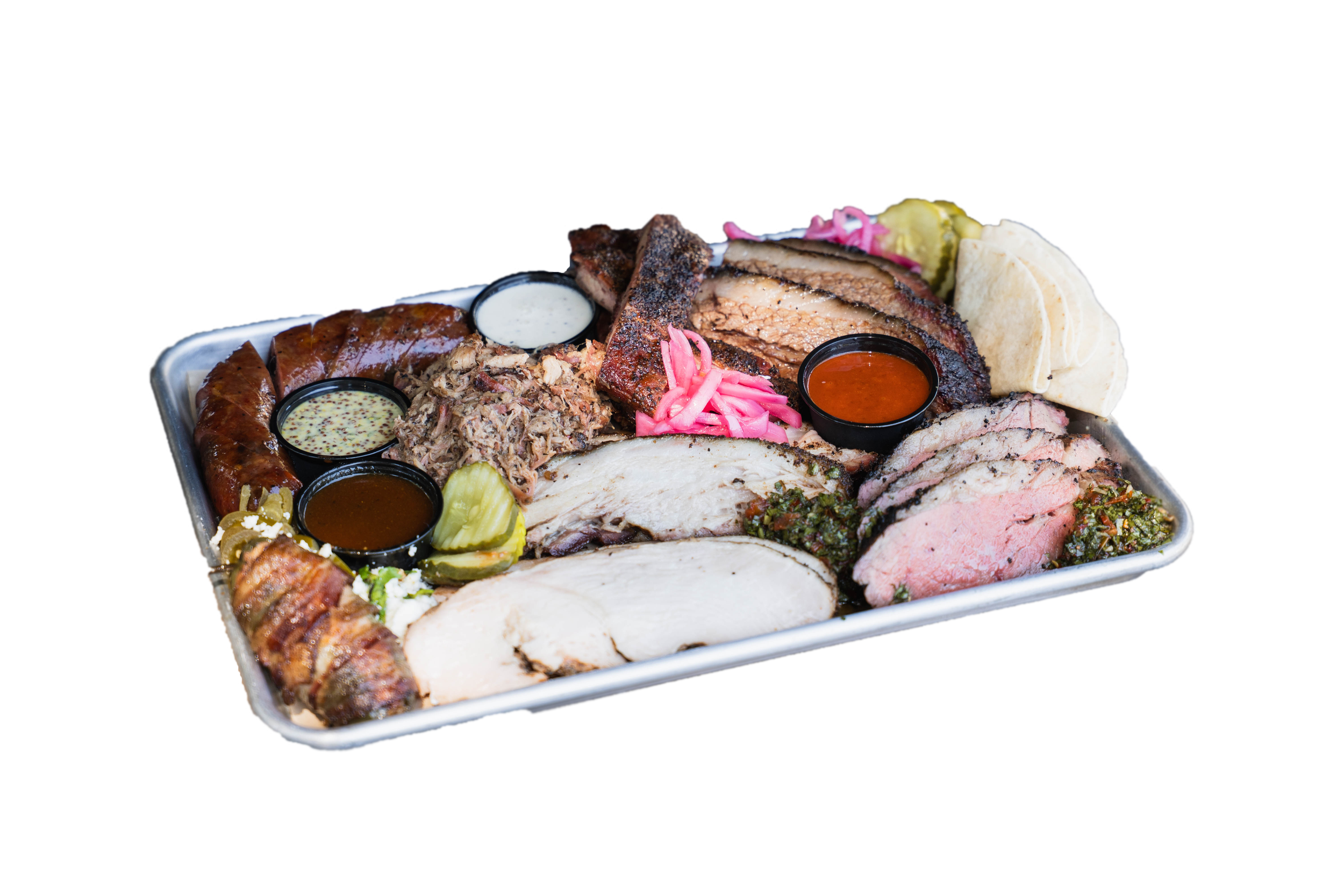 Tray of assorted grilled meats by Hootenanny's BBQ in Brunswick GA, including sliced turkey, beef brisket, sausage, and ribs, garnished with pickles, onions, and served with different dipping sauces.