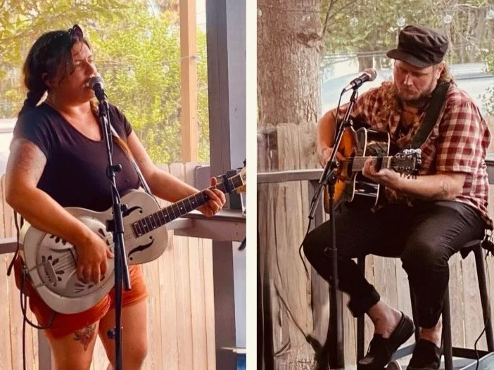 Two musicians performing outdoors, one woman singing and playing guitar, and a man seated and playing acoustic guitar.