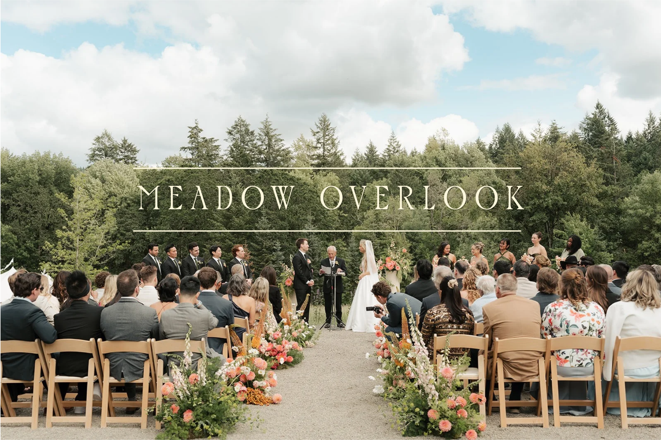 Outdoor wedding ceremony setup with rows of wooden chairs and floral arrangements, set against a backdrop of lush green trees.