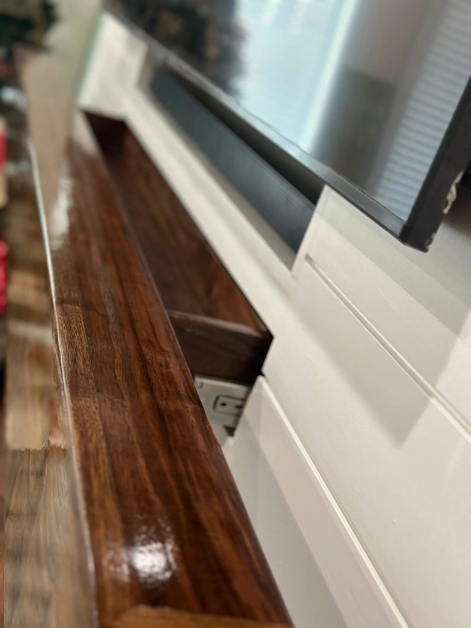 This image displays a close-up of a finished wooden mantel, featuring an outlet.