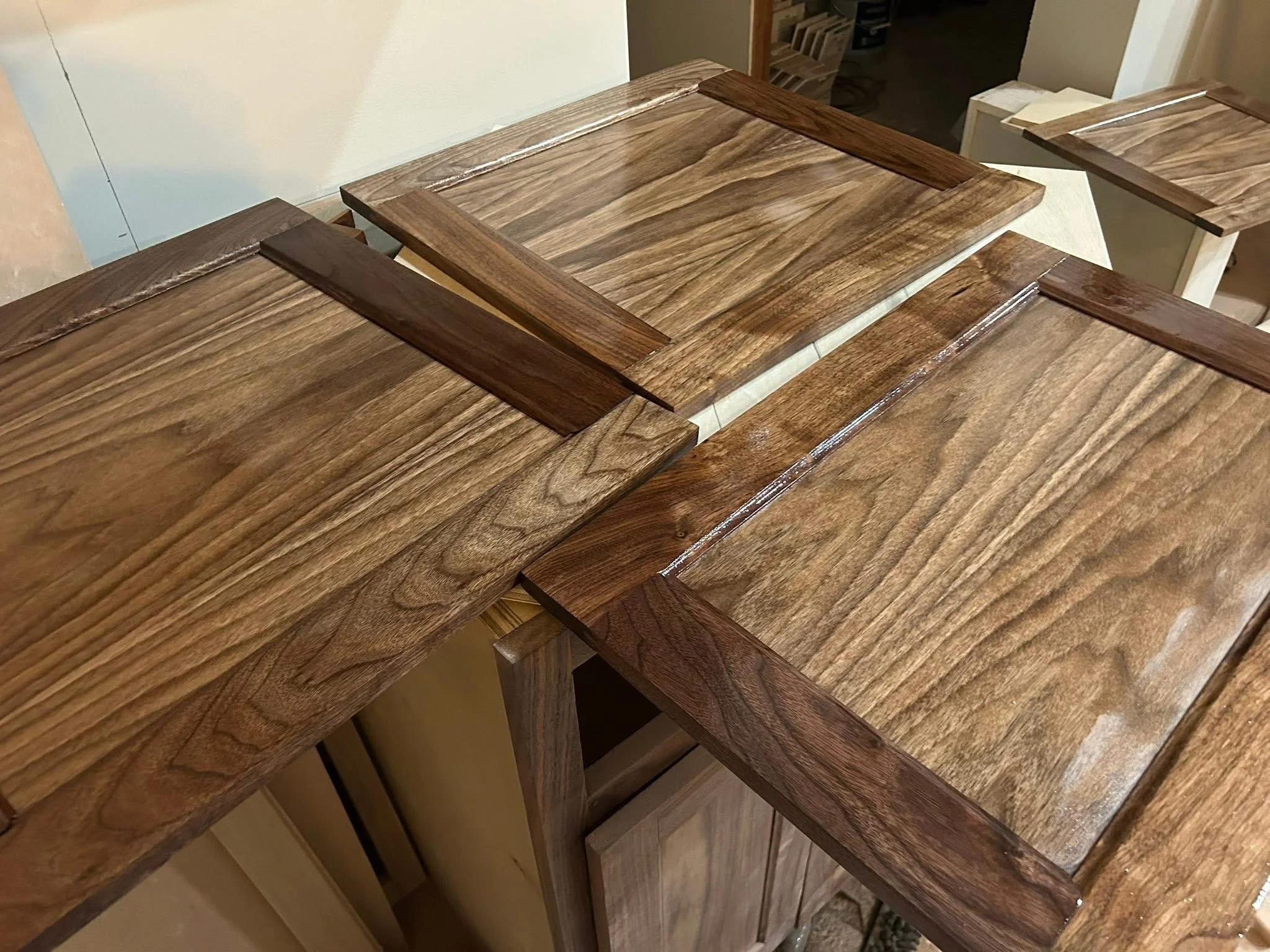 Finished wooden cabinet doors, arranged with visible wood grain and varying shades of brown.