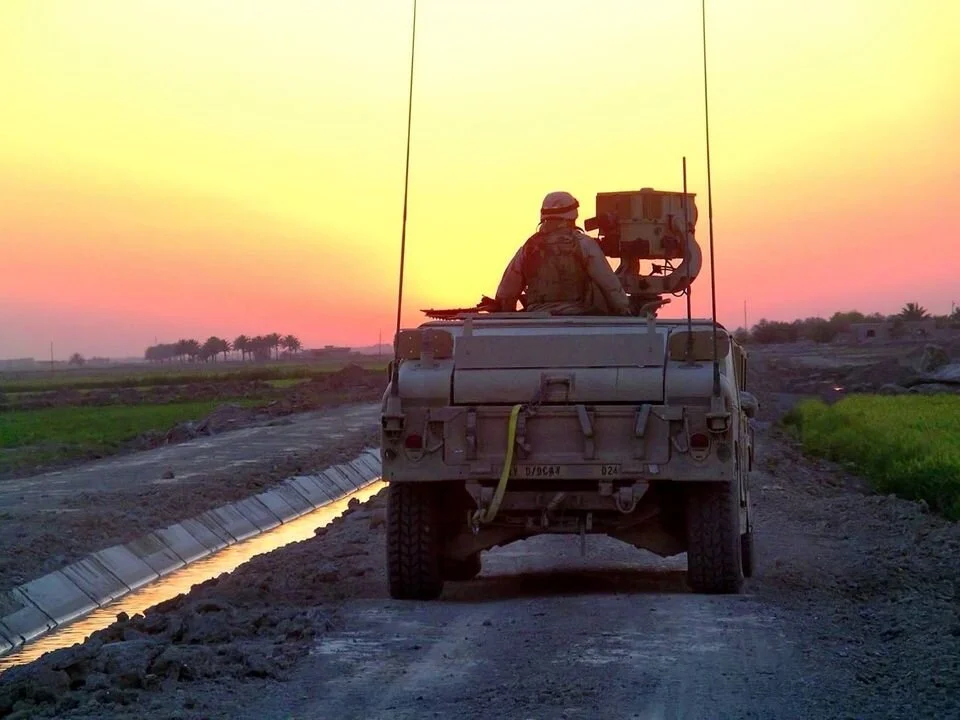 A scout team moving along an irrigation canal at dusk