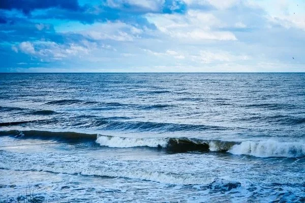 Open ocean with small waves and a cloudy sky.