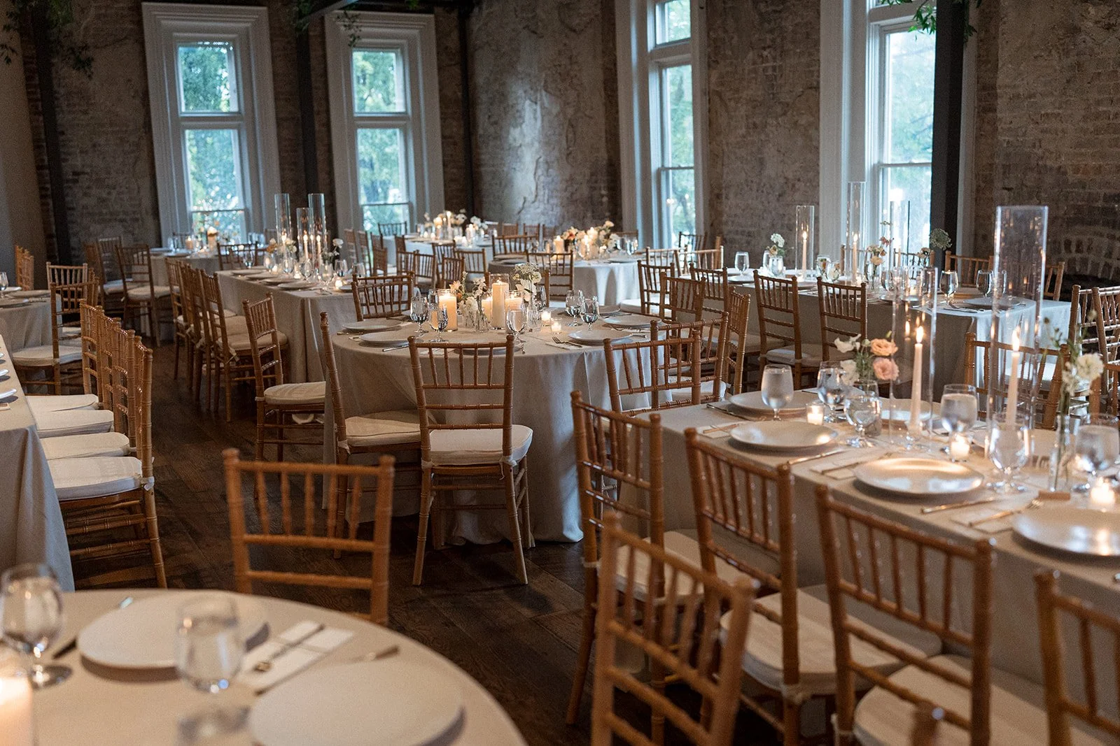 Elegant banquet in the Victorian at the Cordelle with round and rectangular tables set for a special event, decorated with candles, glassware, and floral centerpieces. Wooden chairs surround the tables, and large windows let in natural light.