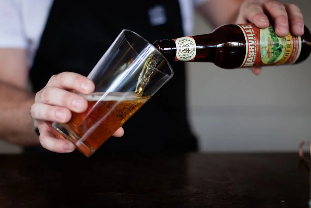 Craft beer service at the Cordelle Bar in Nashville Person pouring beer from a bottle into a glass.