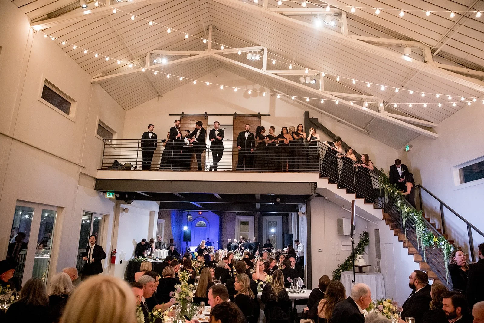 Cordelle Guests in formal attire at a wedding reception, with a band playing on the upper level and guests dining on the lower level. Modern elegance event space