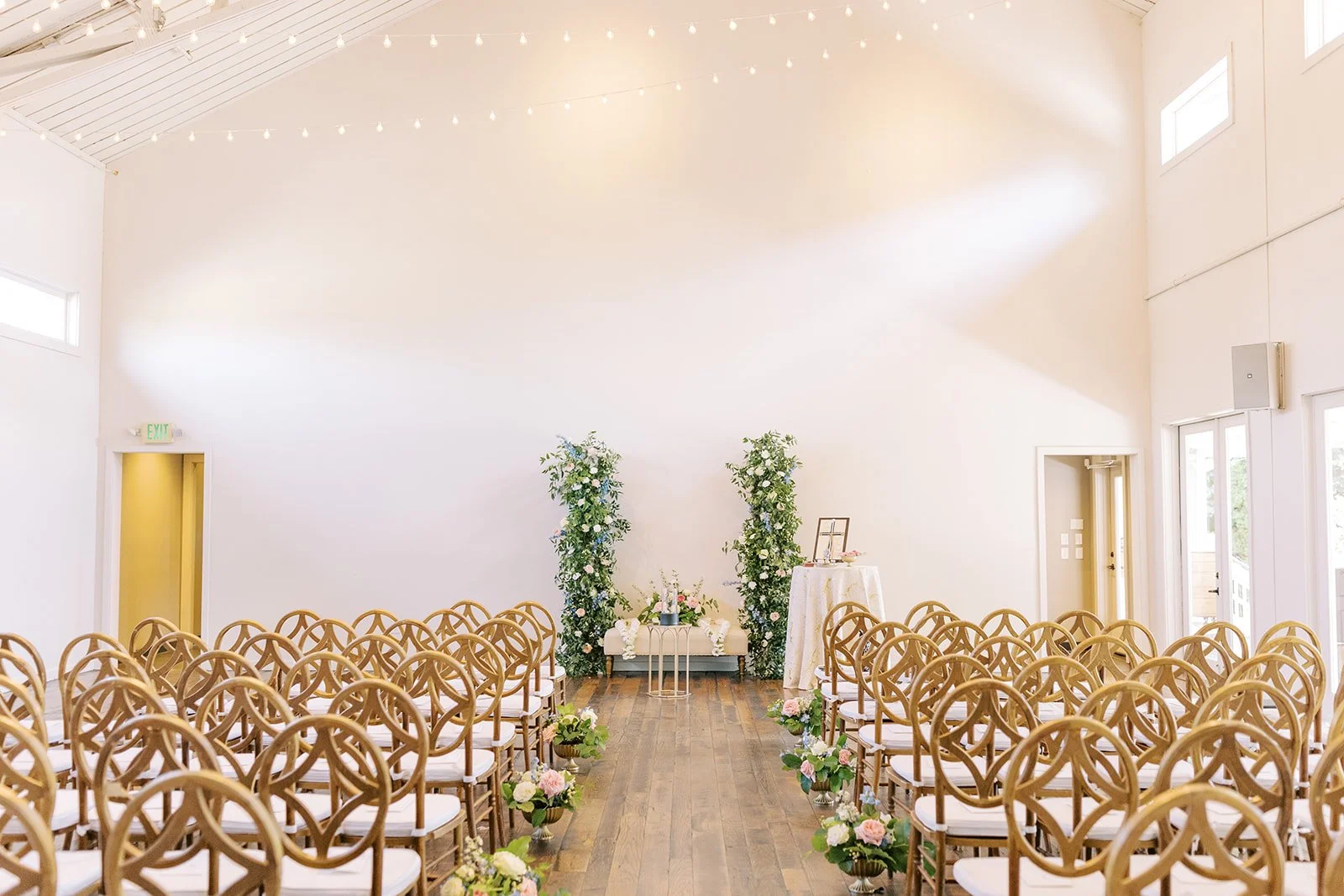 Wedding ceremony setup in the bright, open Great hall at the Cordelle Downtown Nashville Award Winning Venue with rows of wooden chairs, floral arrangements, and a decorated altar with greenery and flowers.
