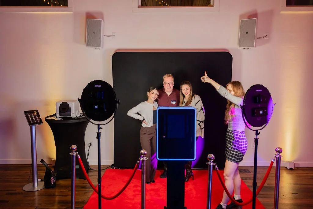 Corporate event at the Cordelle in Downtown Nashville photo at a photobooth station with a black backdrop, colored lighting, and two large circular lights.