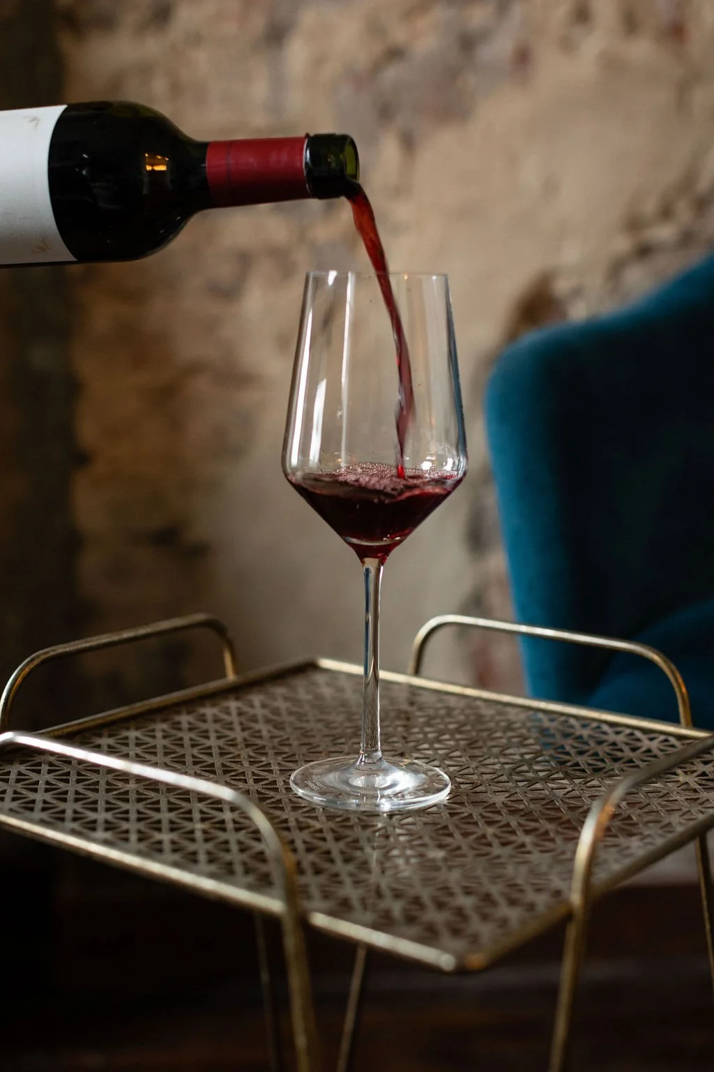 Event Bar service in Nashville at the Cordelle Red wine being poured into a glass on a metal tray against a rustic brick wall background.