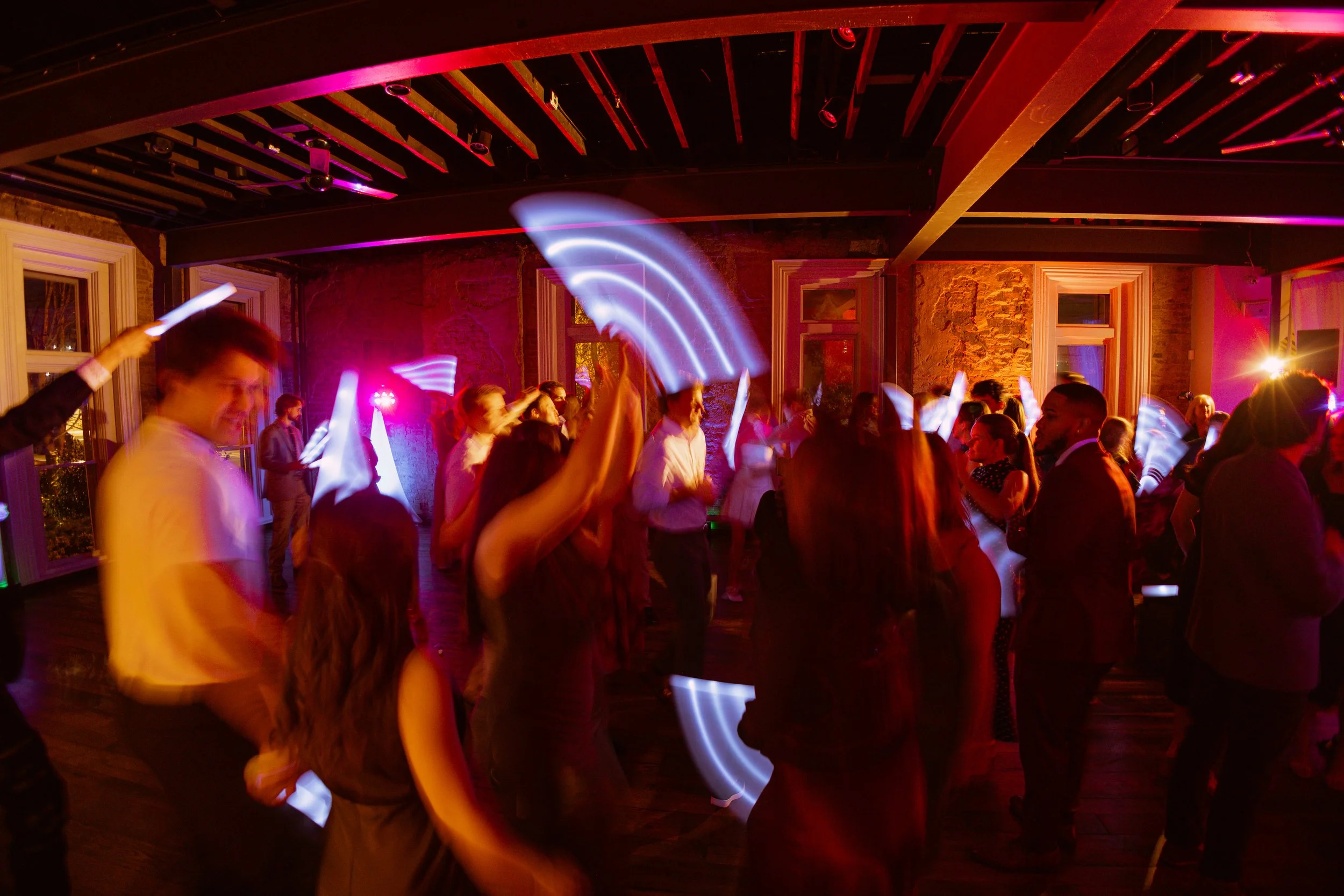 Dance party in the Victorian at the Cordelle with People dancing at a party or event with colorful lighting and a rustic brick wall interior.