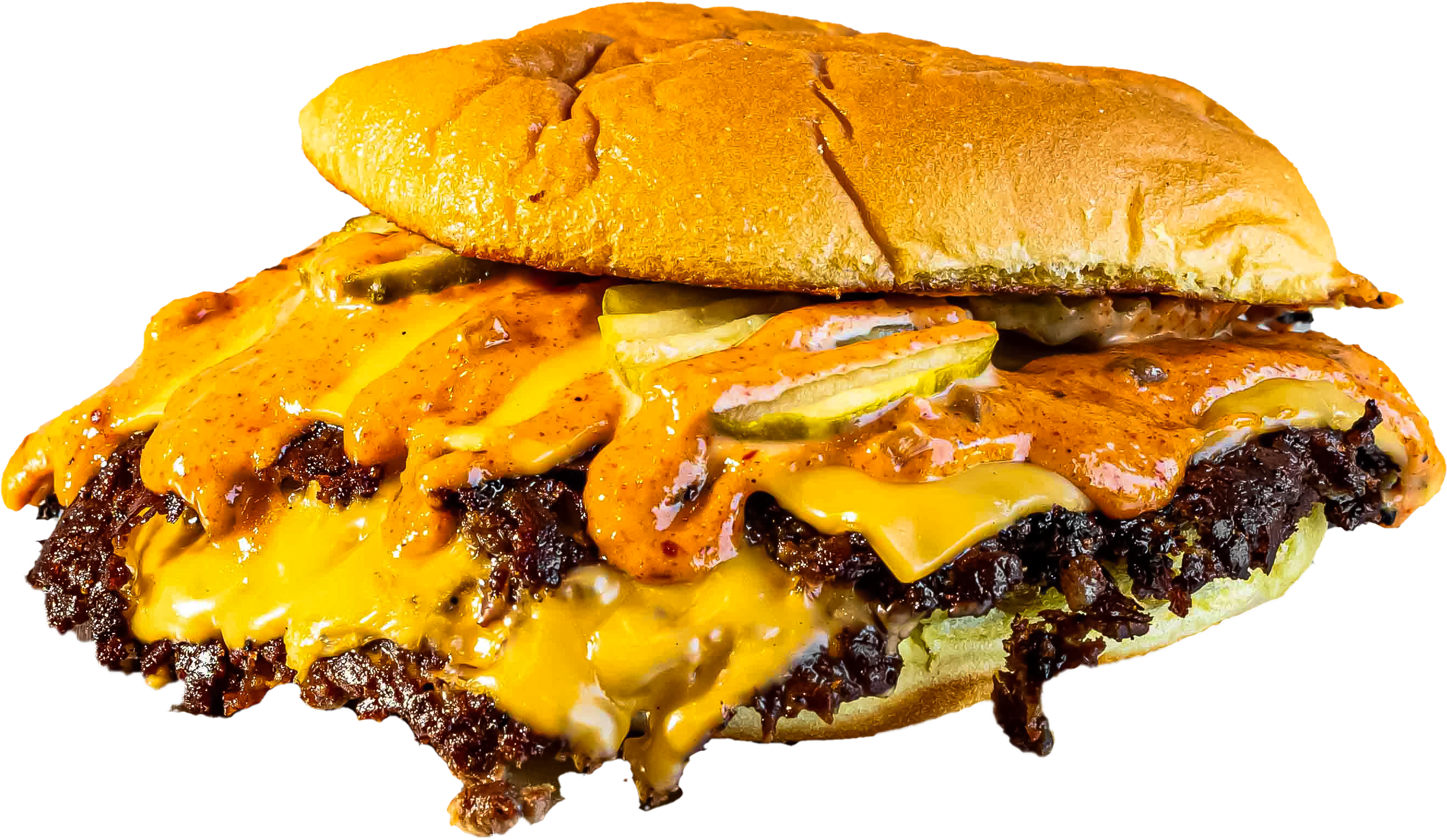 Close-up of a cheeseburger with melted cheese, pickles, and barbecue sauce, served on a toasted bun.