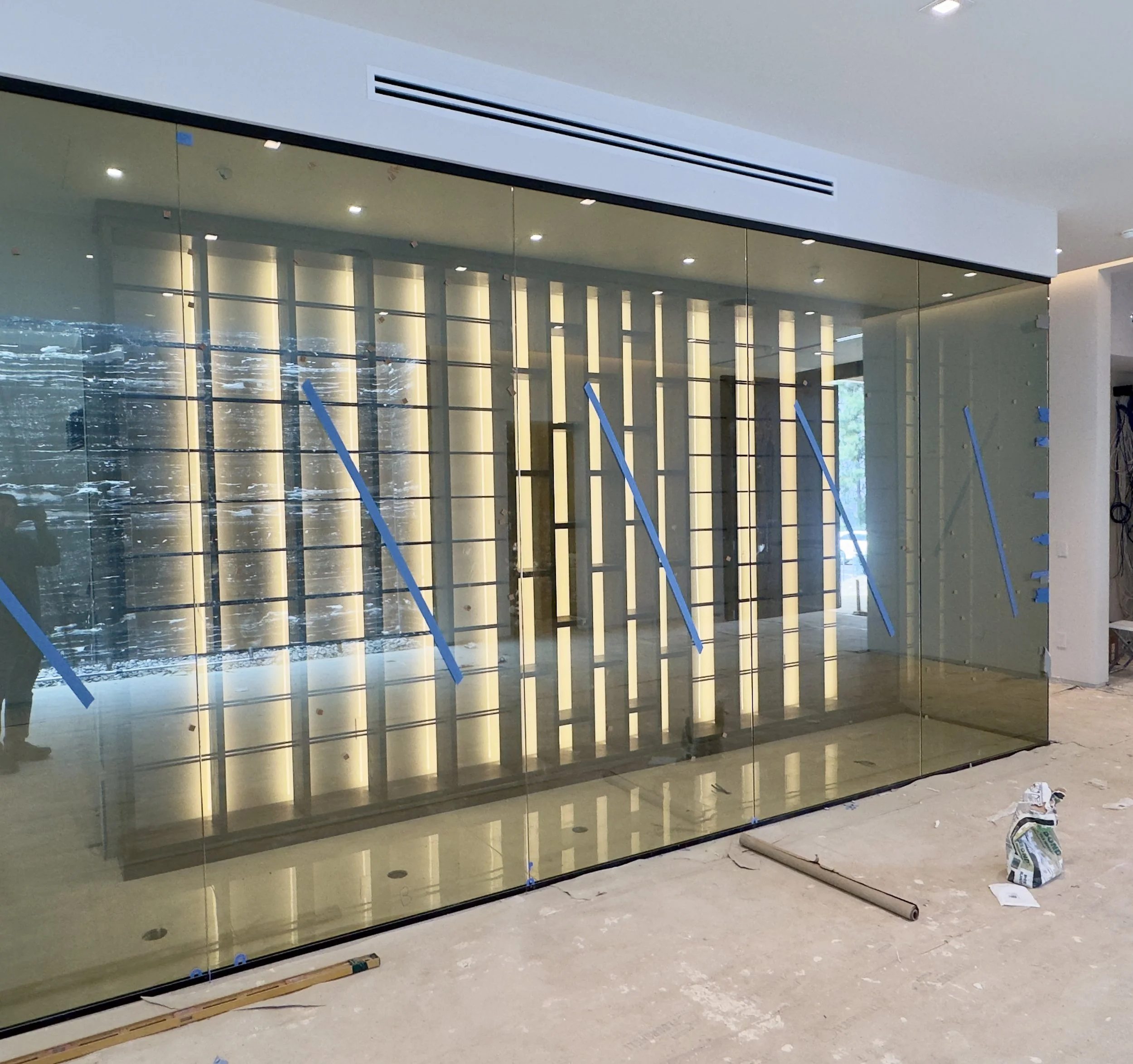 Under construction area with a glass wall, construction tools, and materials on the floor.