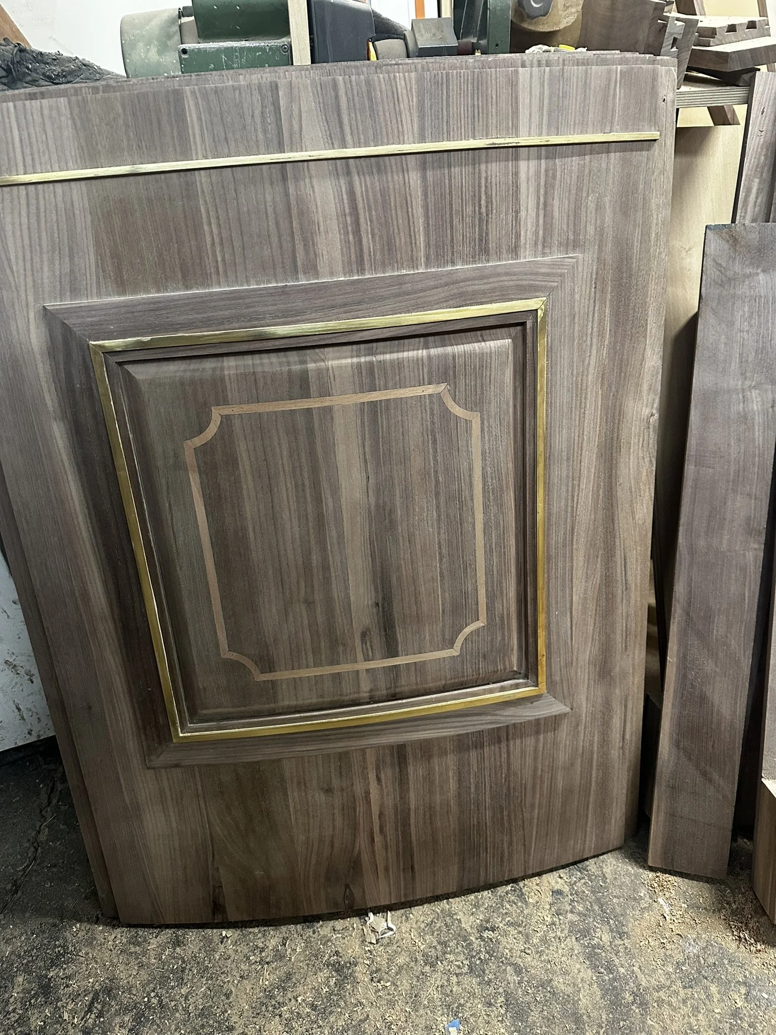 Close-up of curved bespoke walnut panels with mahogany inlay and brass detailing for a custom round home bar by Ironwood Furniture Studio.
