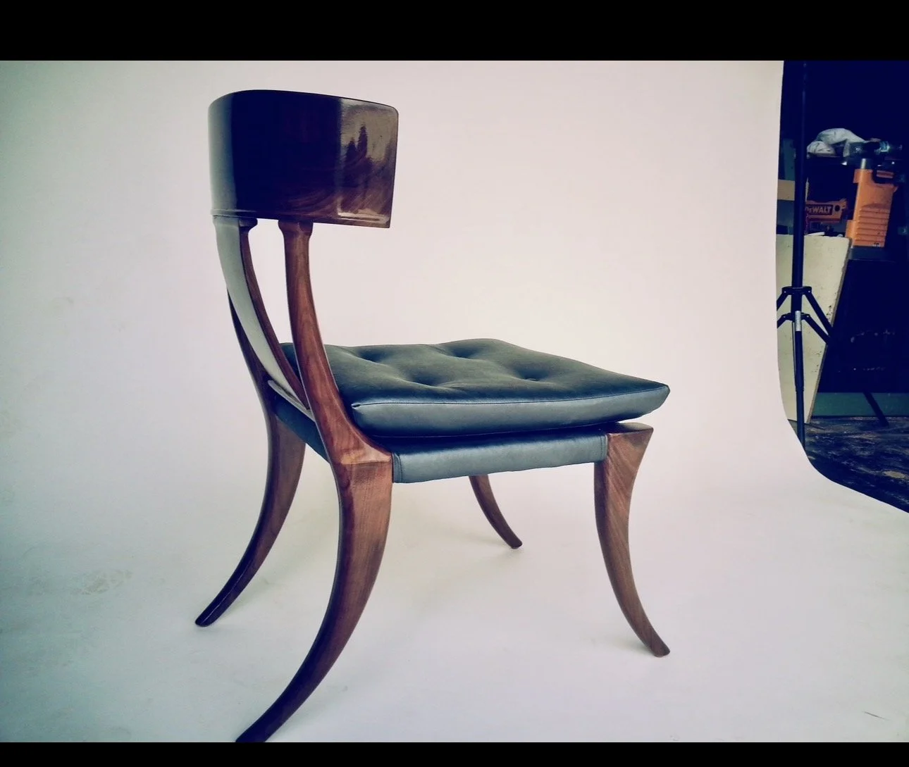A vintage wooden chair with curved legs and a leather cushioned seat and backrest, set against a plain white background.