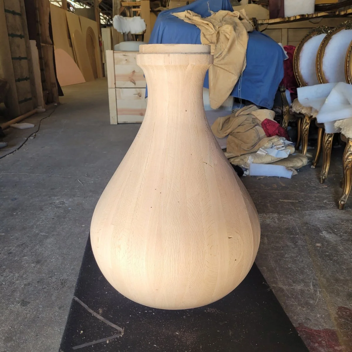 A wooden vase in the workshop, surrounded by furniture and fabric materials.
