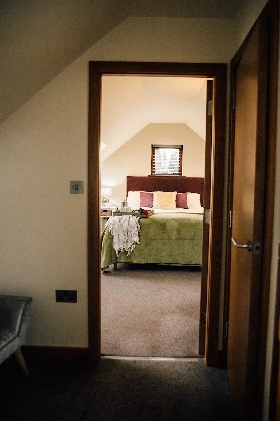 View through a doorway into a bedroom with a bed, pillows, and a window behind.