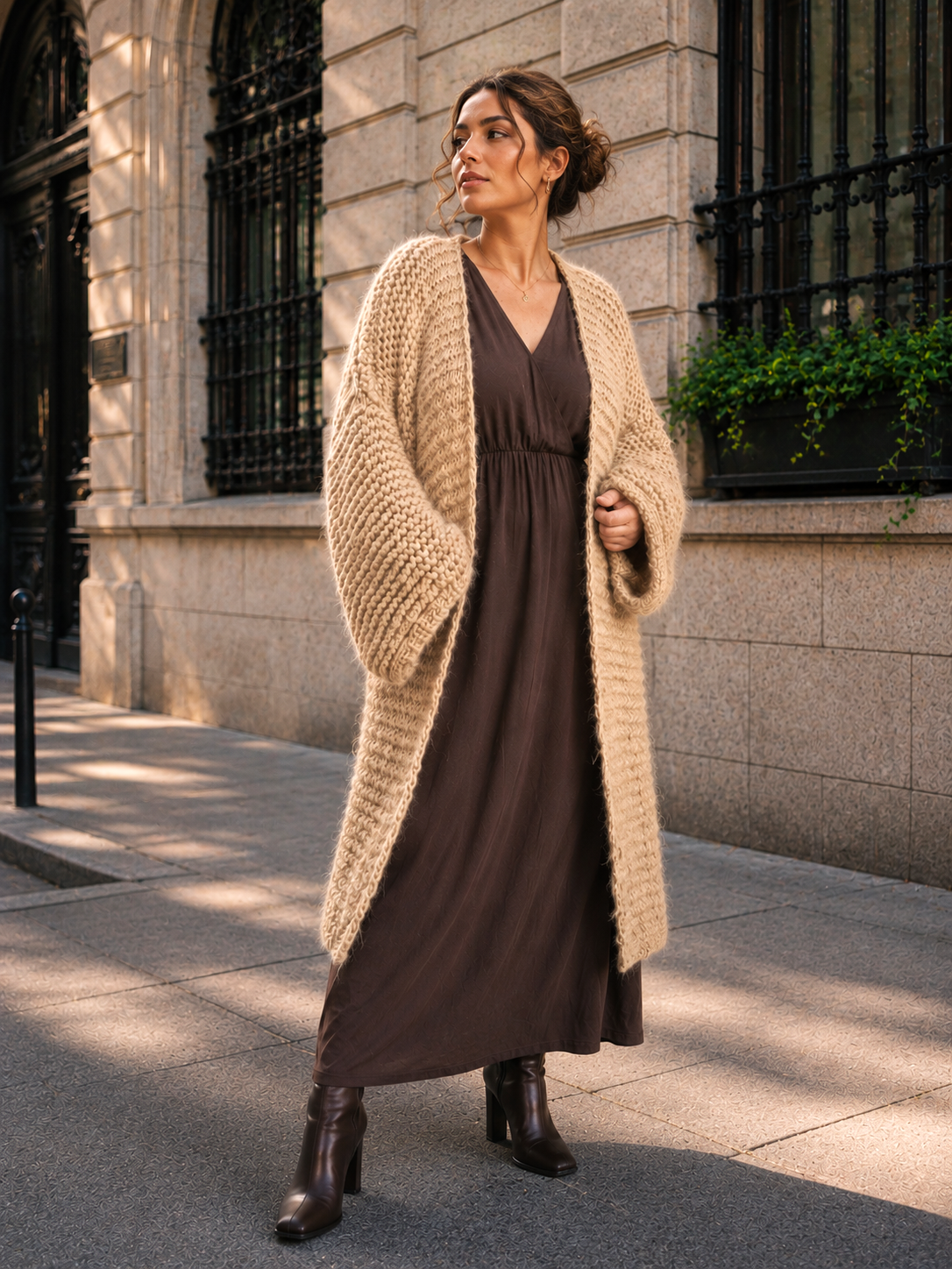 chunky beige long oversized cardigan worn by pretty woman over long brown dress, chic allure, elegant look, high heel boots, urban casual outfit