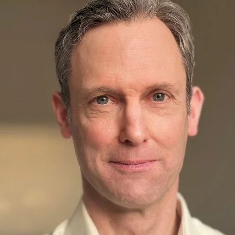 Simon with kind eyes and a subtle smile.