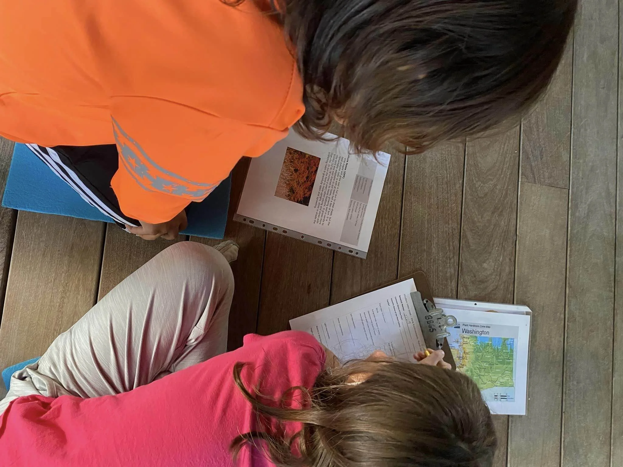People sitting at a table, looking at maps and informational signs about Washington state, with brochures and informational materials on the table