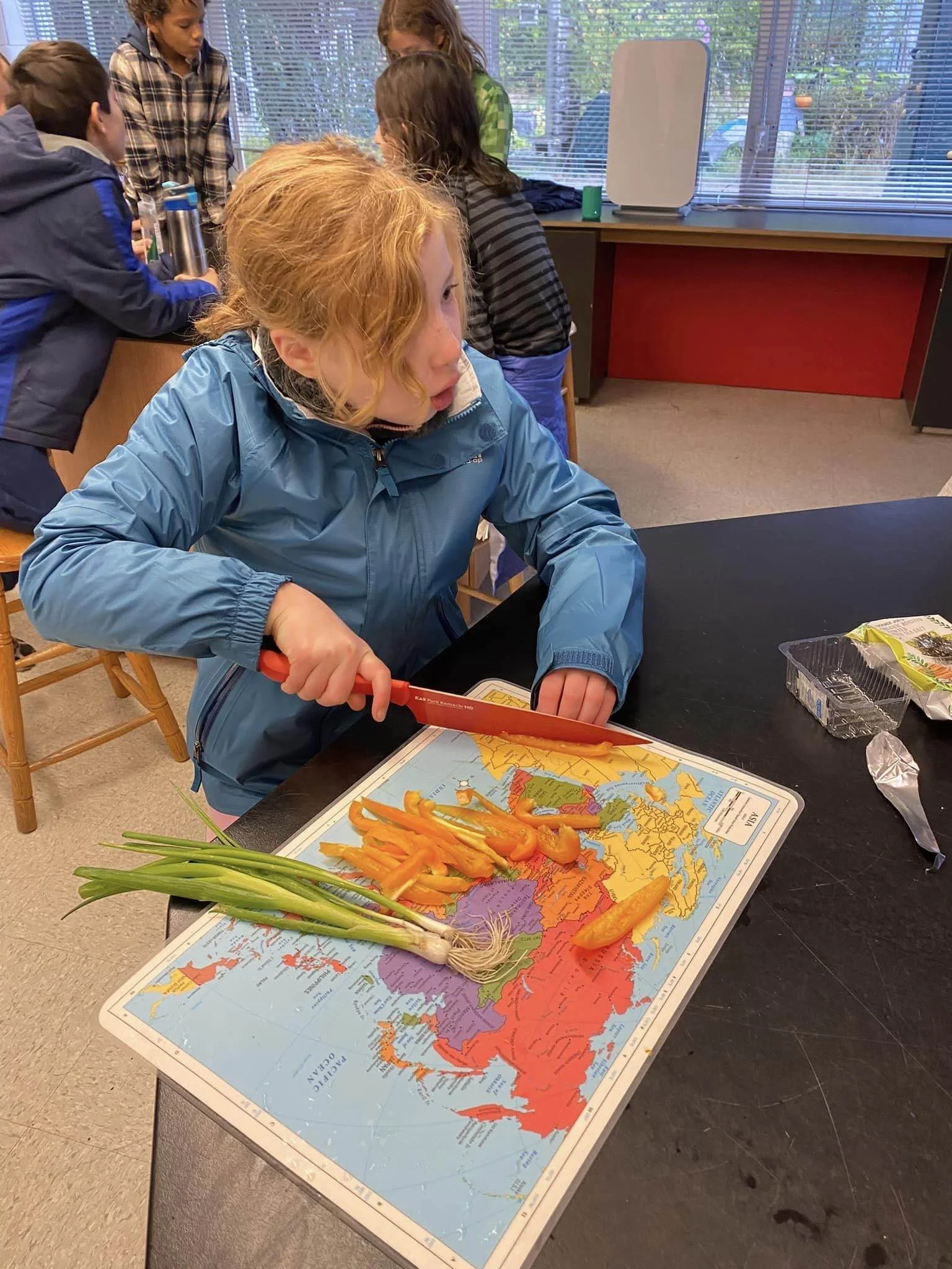 Children in a classroom preparing vegetables on a map of Russia.