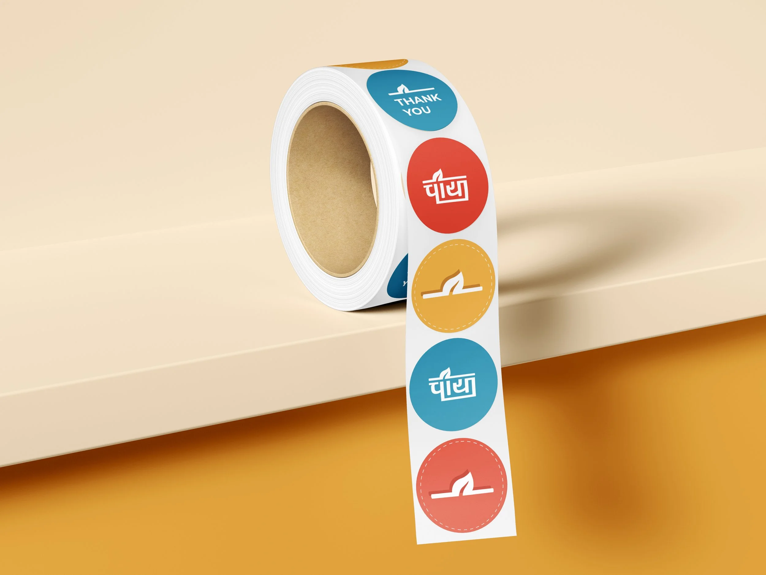 Roll of decorative tape with colorful circular patterns featuring icons and text, placed on a beige surface with some tape unwound.