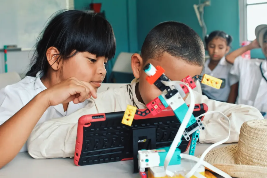 Children in a classroom working on a robotics project with a tablet and LEGO Mindstorms robot