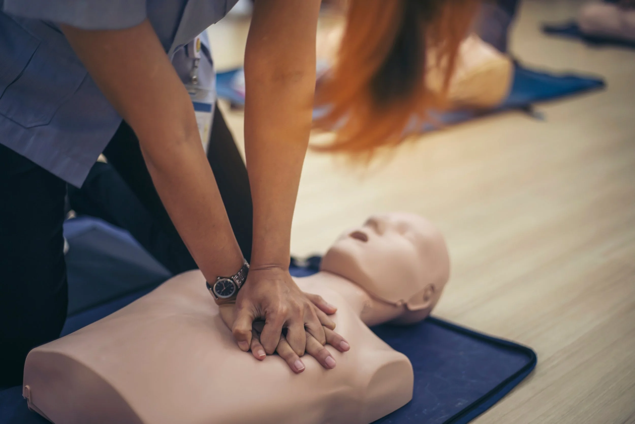 A person performing CPR on a practice mannequin during a training session.