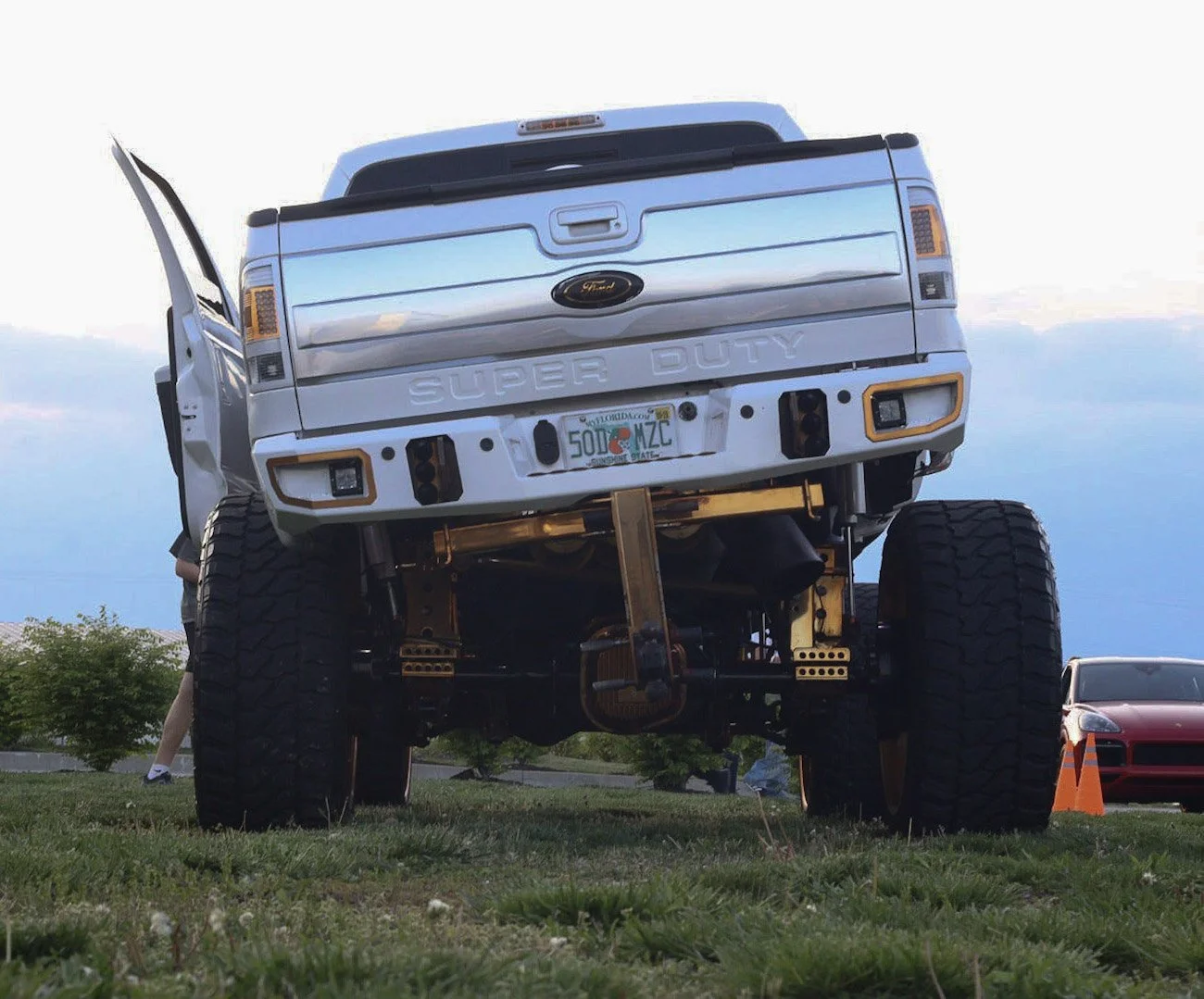 A lifted Ford Super Duty pickup truck on display outdoors with open front door and aftermarket suspension.