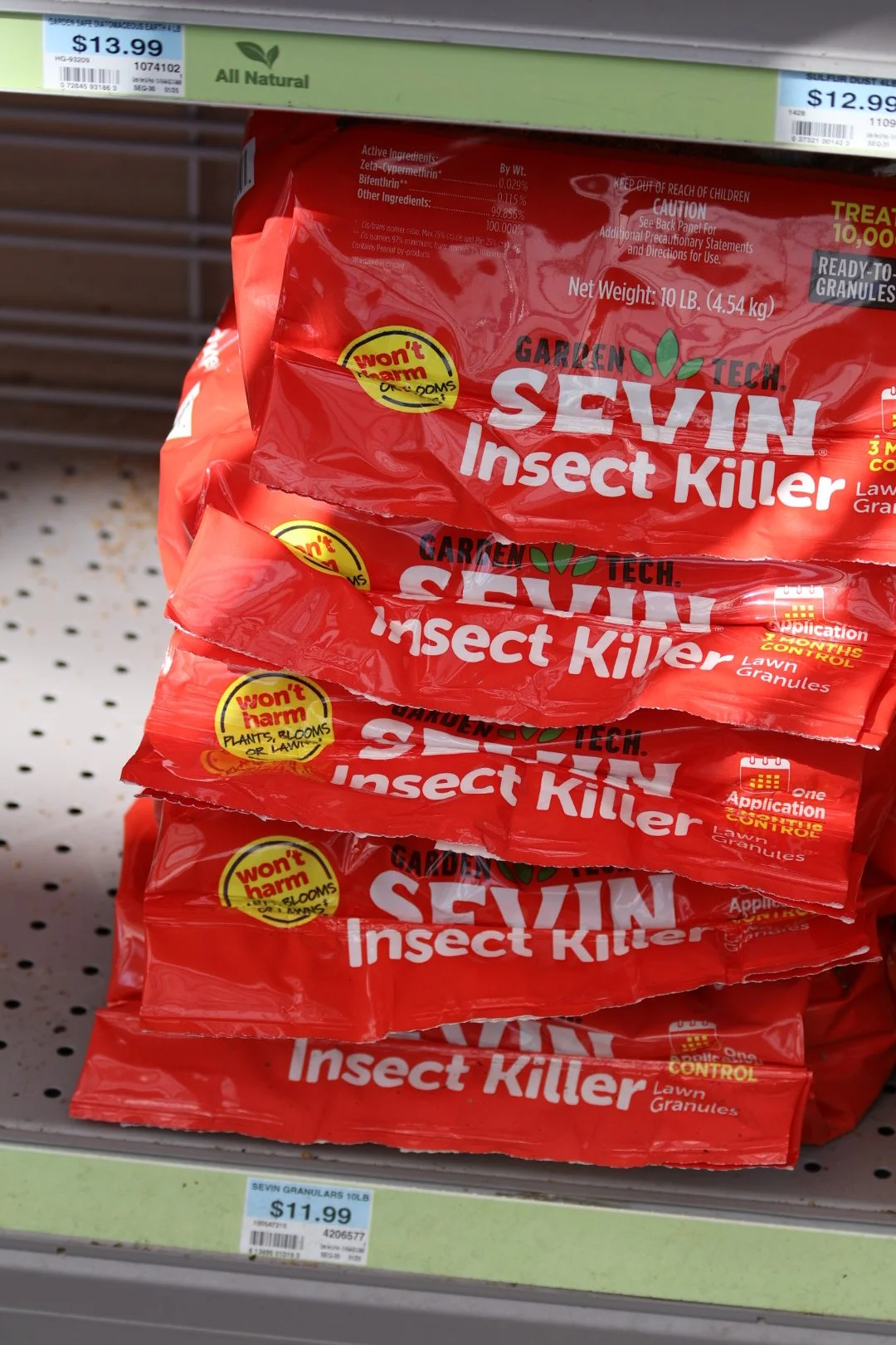 Stacked red bags of Garden Tech SEVIN Insect Killer lawn granules on store shelf indoors.