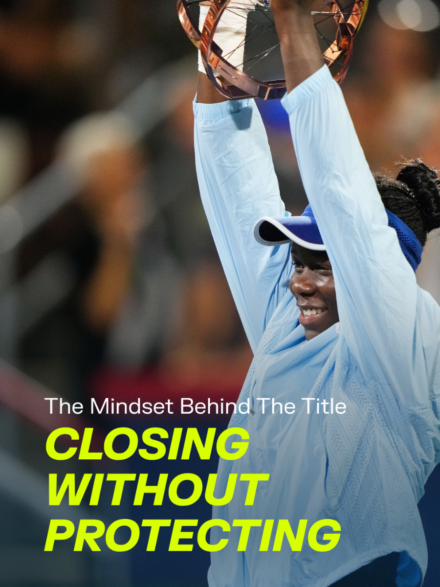 Une athlète féminine souriante en tenue de sport blanche et visière, levant une coupe de tennis, lors d'une cérémonie de victoire.