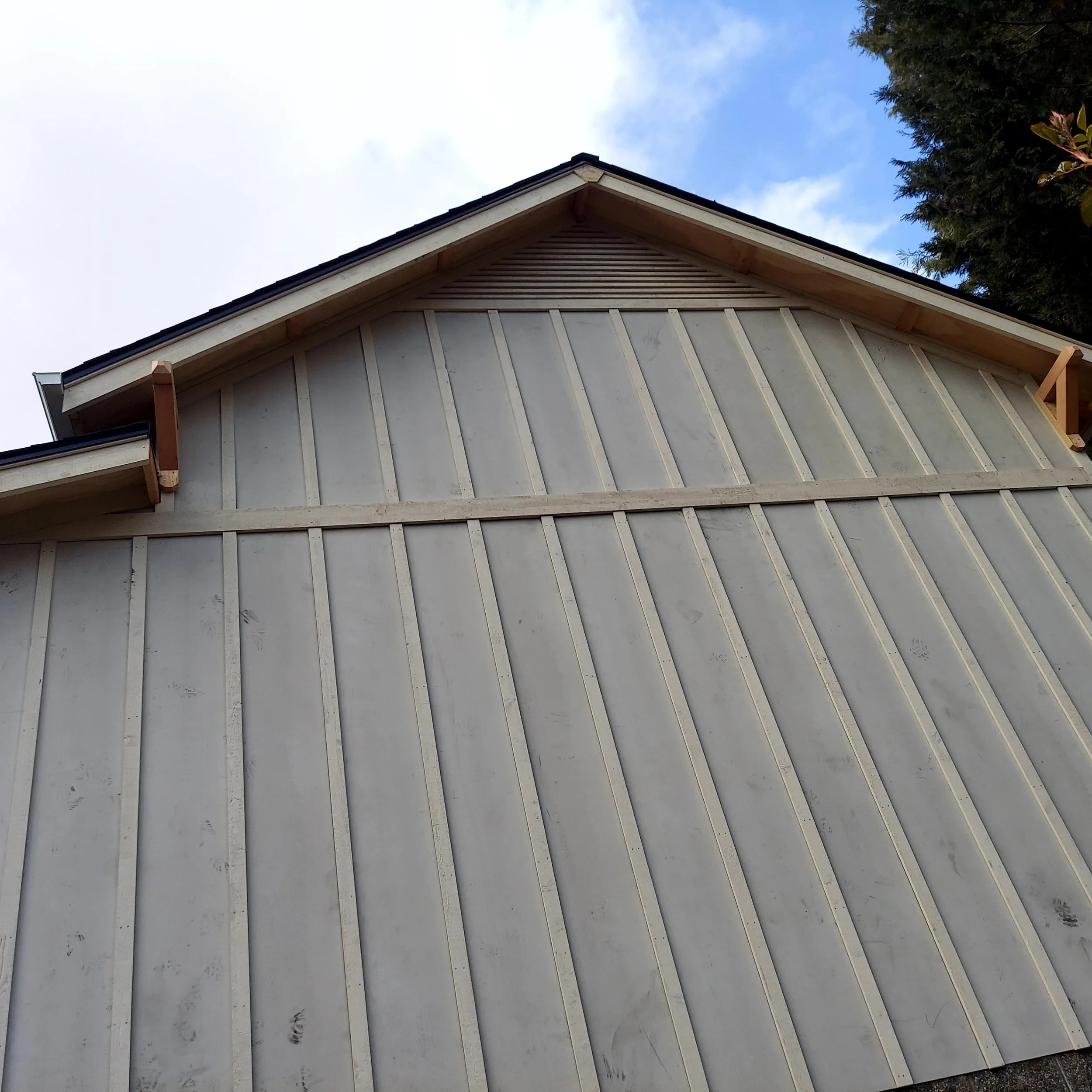 Freshly installed siding on a blue outbuilding