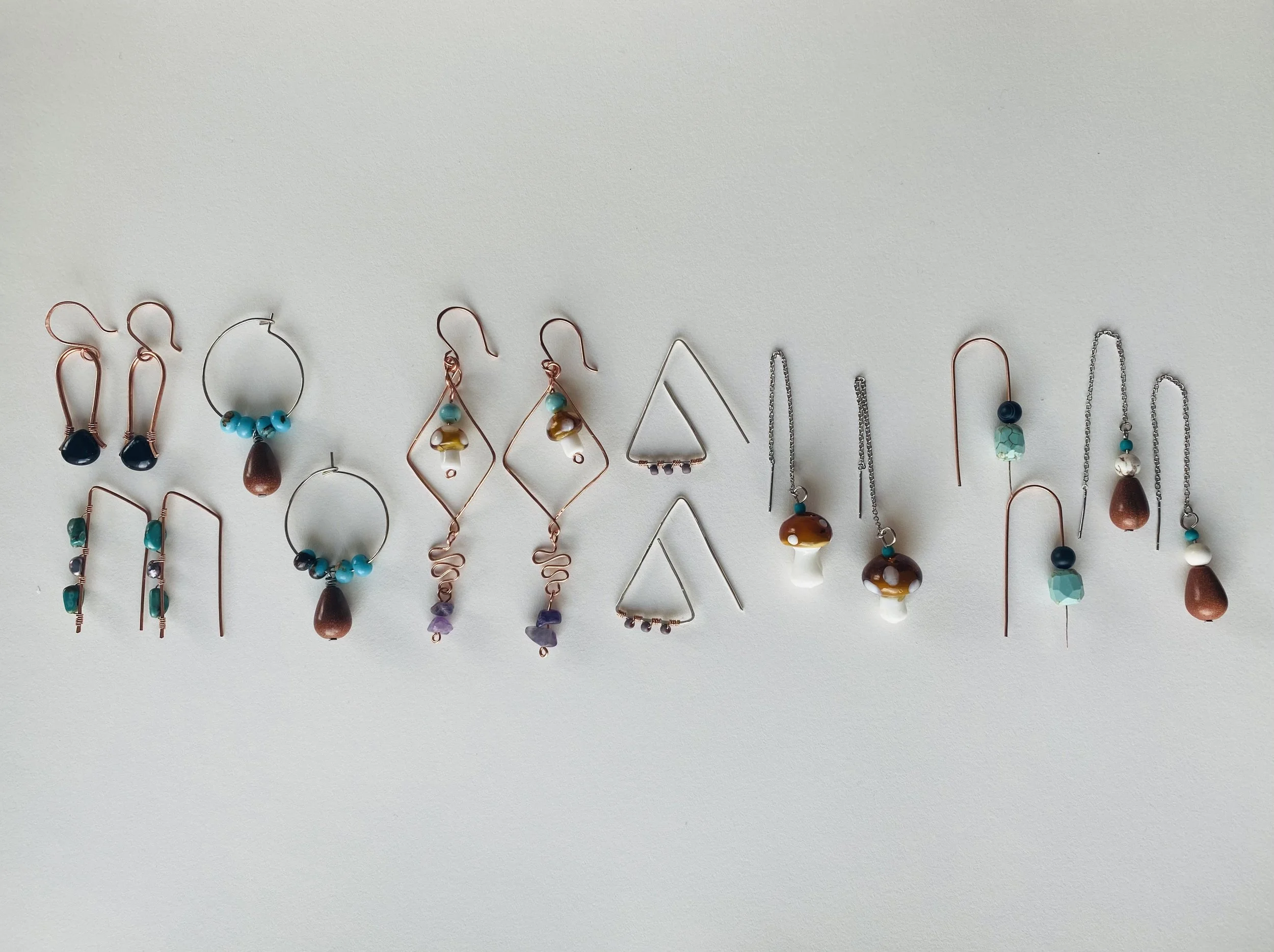 A collection of earrings with various designs and colors laid out on a white surface.