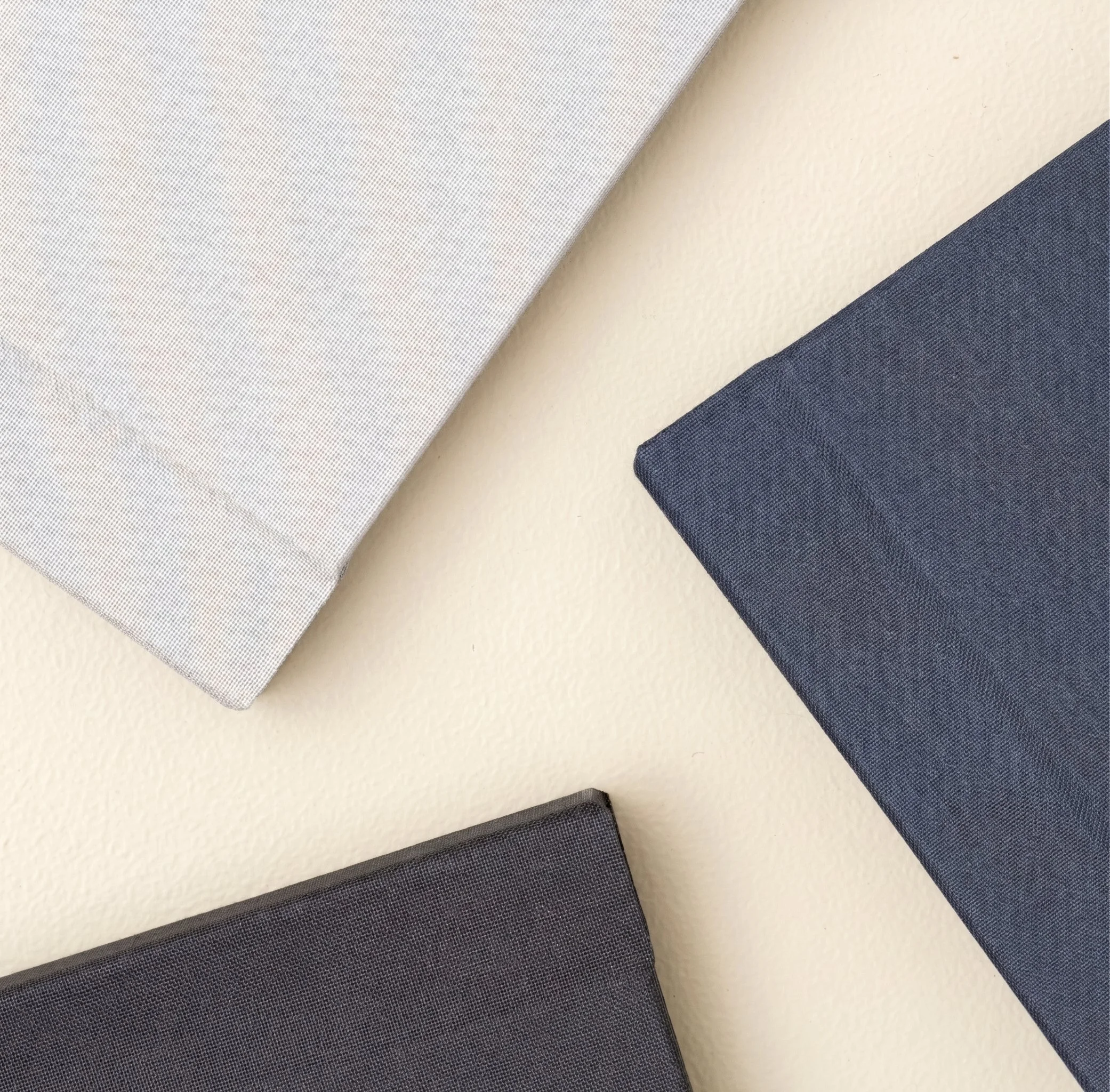 Close-up view of various fabric swatches in shades of gray, beige, and black, arranged on a flat surface.