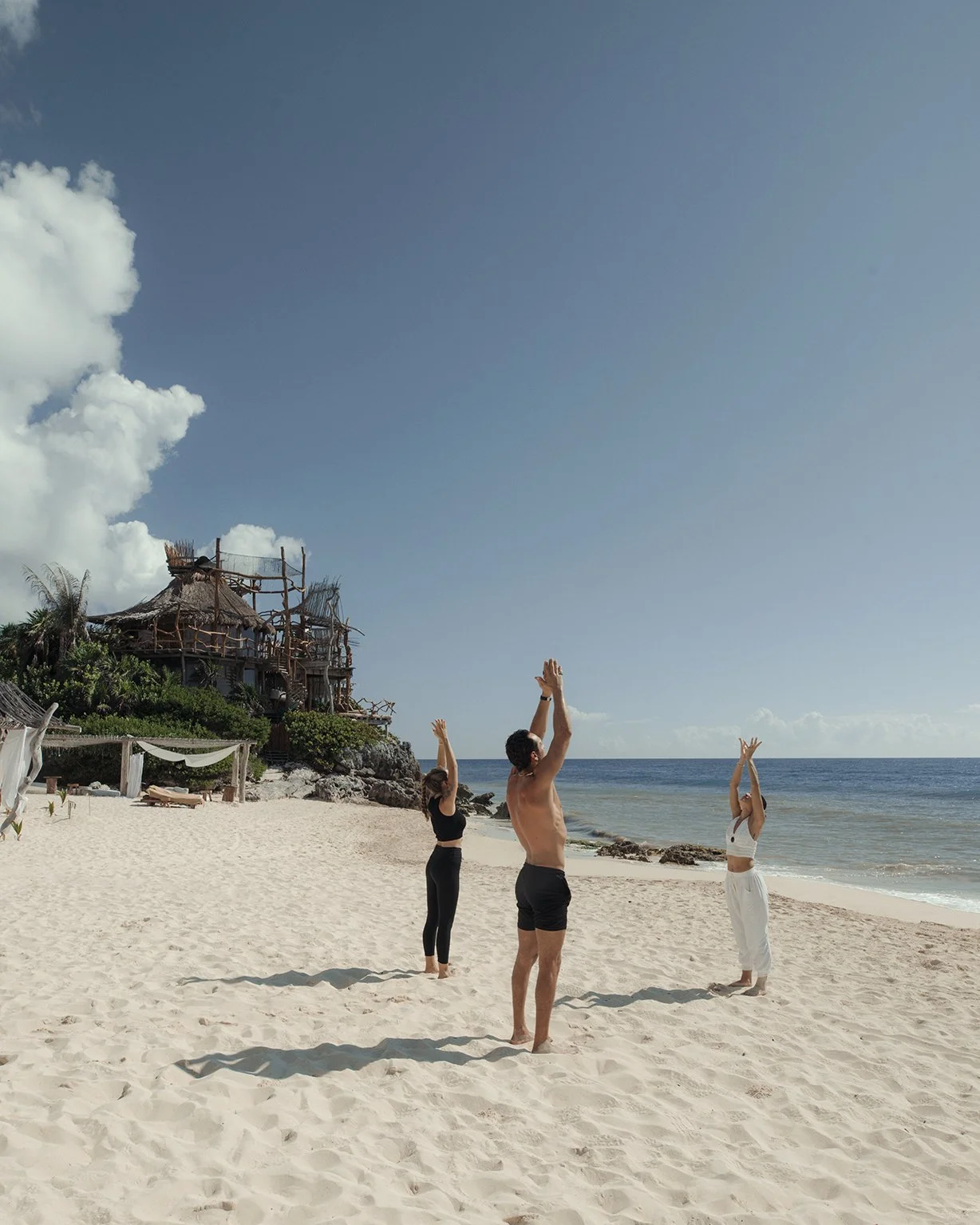 Práctica de yoga en playa de arena blanca. Fotografía de hospitalidad de lujo en Tulum.