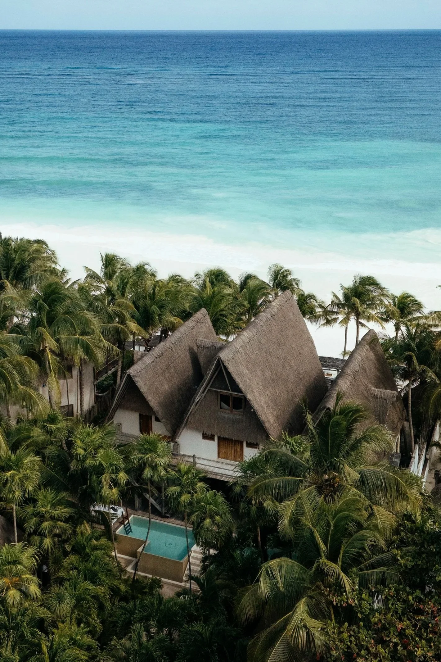 Vista aérea de hotel frente al mar turquesa. Arquitectura de lujo en Riviera Maya.