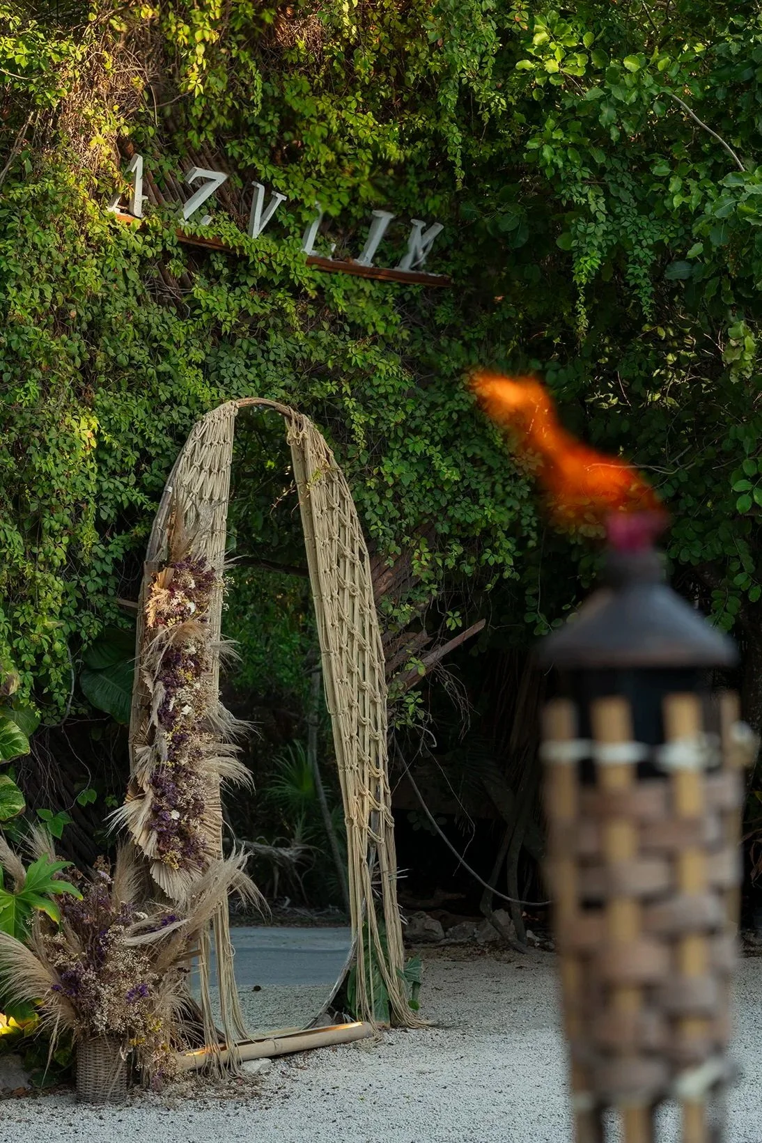 Entrada selvática con espejo y fuego en hotel Azulik, Tulum. Fotografía de hospitalidad de lujo.