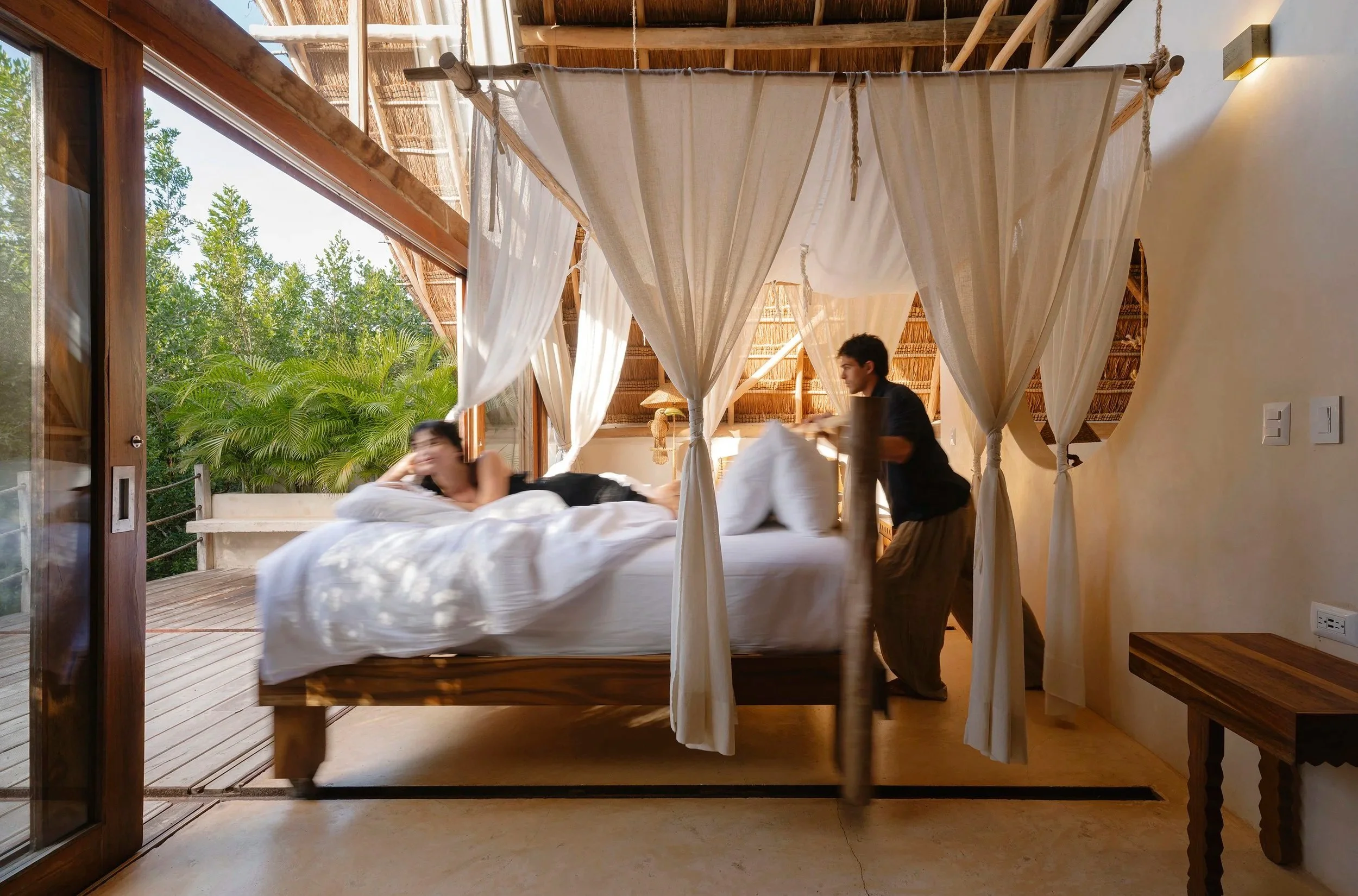 Interior de suite boutique con cama de dosel y madera rústica. Arquitectura hotelera en Tulum.