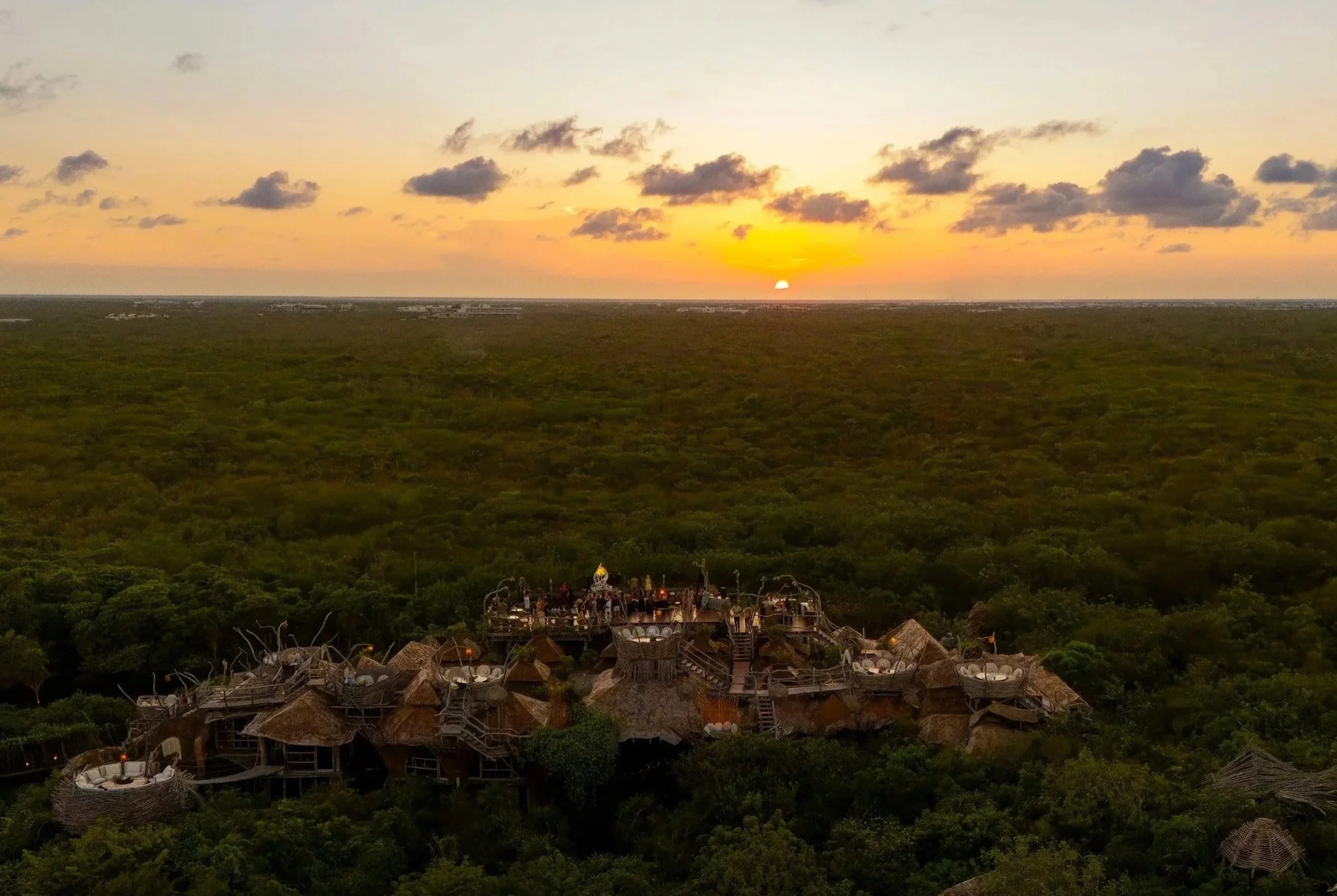 Vista aérea de hotel boutique inmerso en la selva durante el atardecer. Hospitalidad de lujo en Tulum.