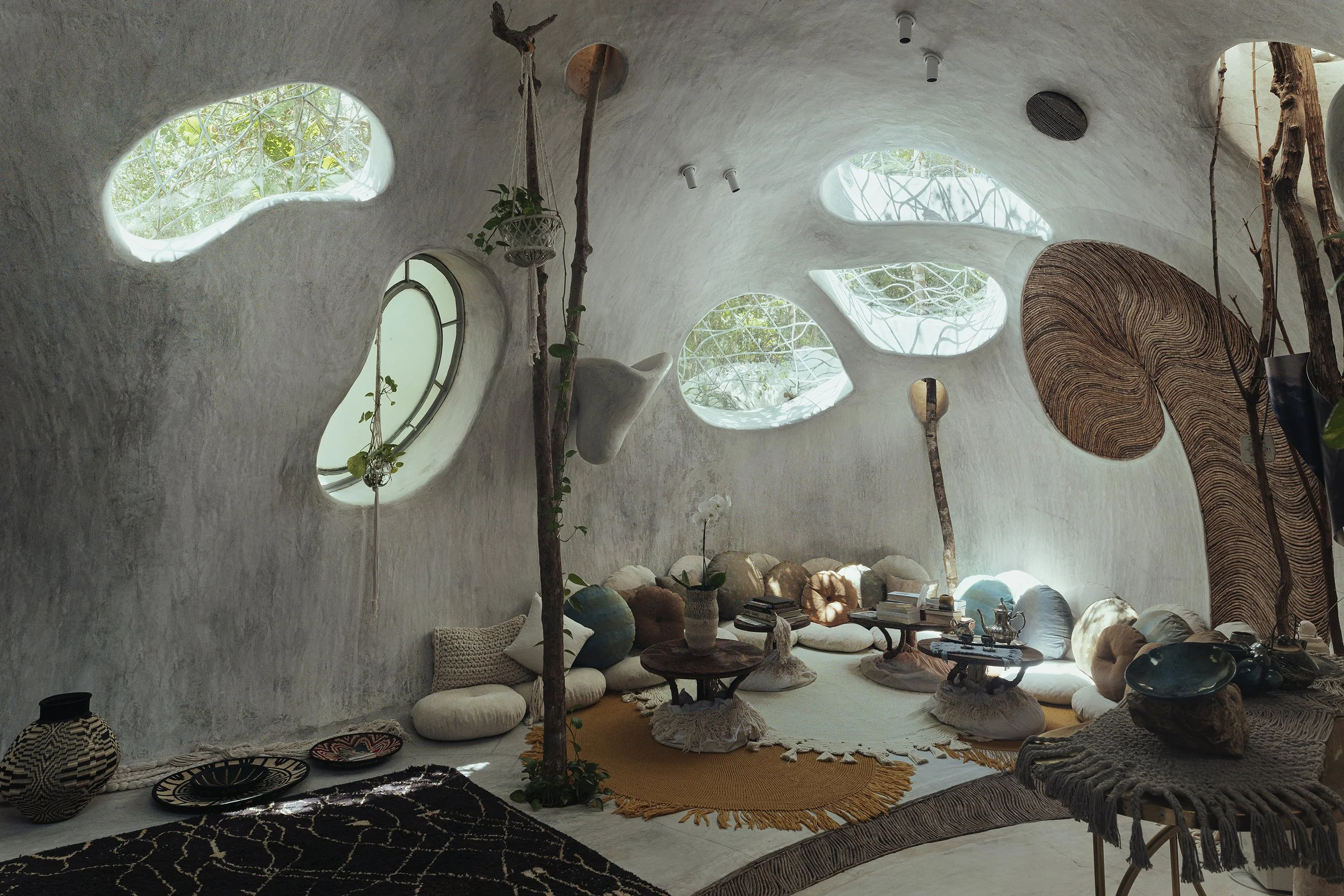 Arquitectura interior orgánica con ventanas irregulares y luz natural. Documentación de espacios en Tulum, México.