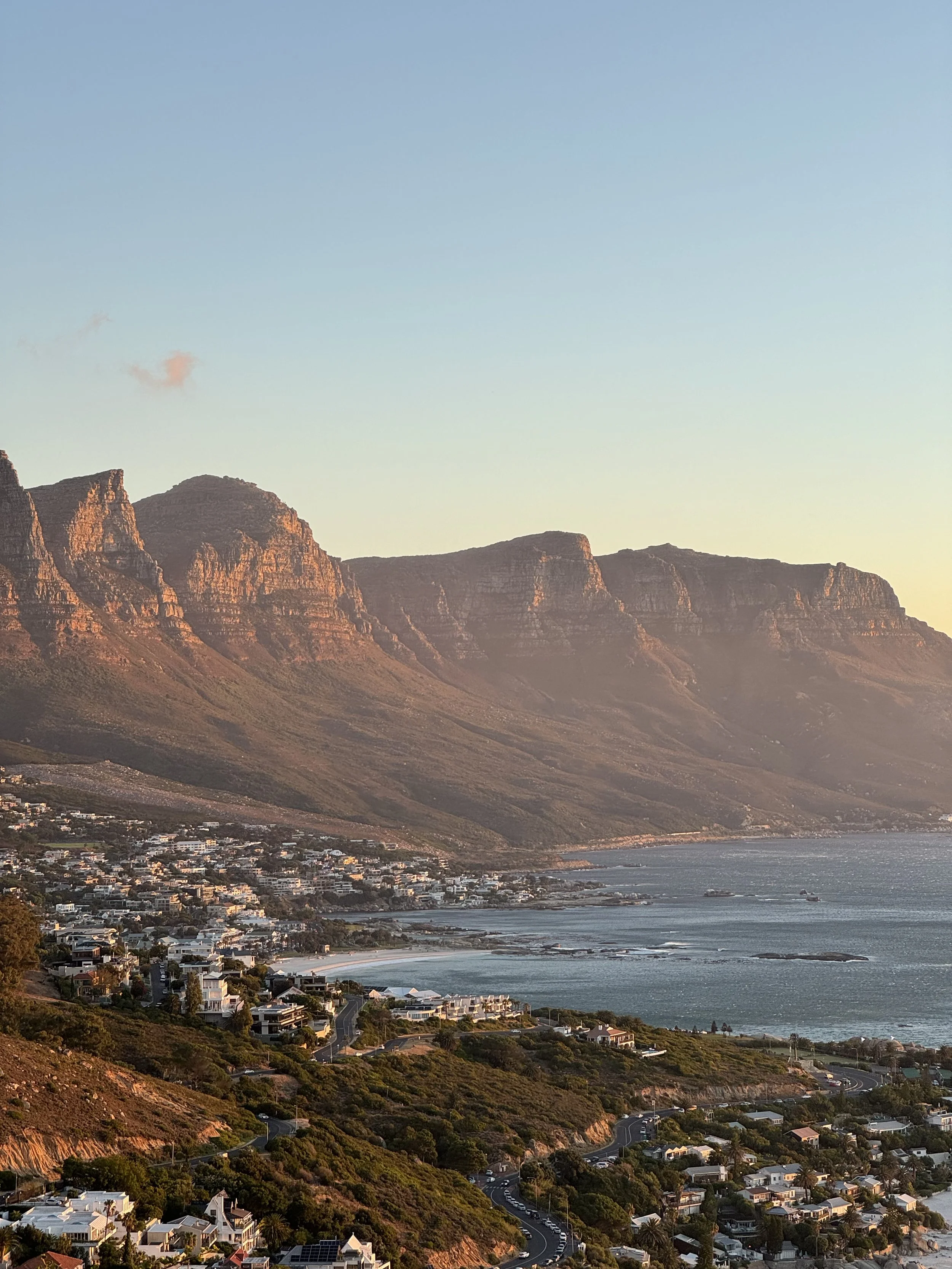 Sunset over coastal mountains with a town near the shoreline