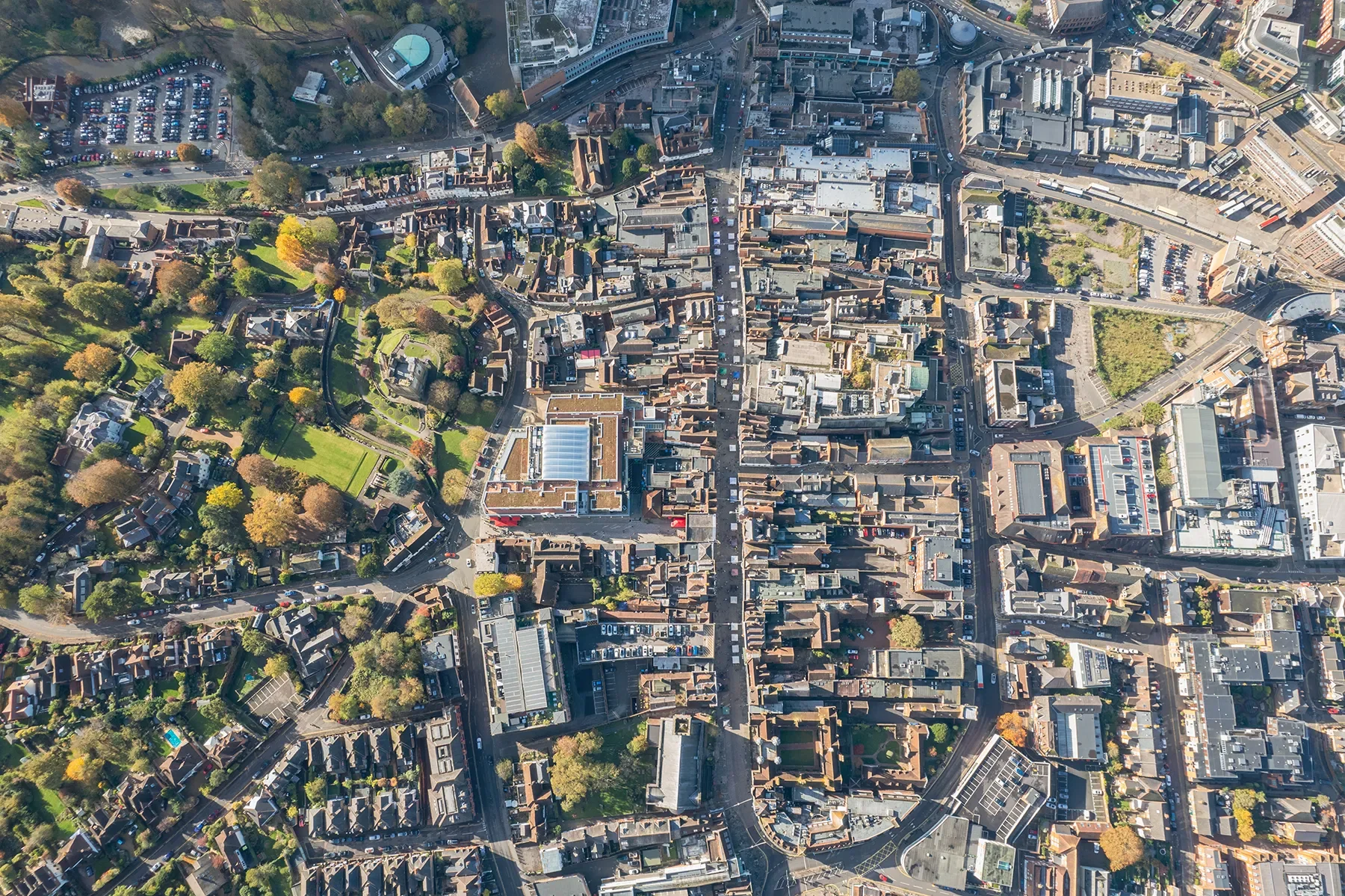 An aerial view of a city with a mix of densely packed buildings, streets, and green spaces, including trees and parks.