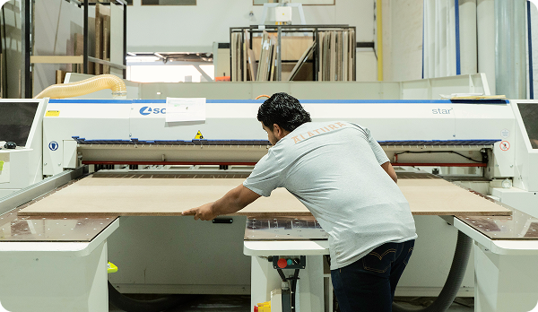 Hombre operando una máquina de corte de madera en un taller de carpintería.