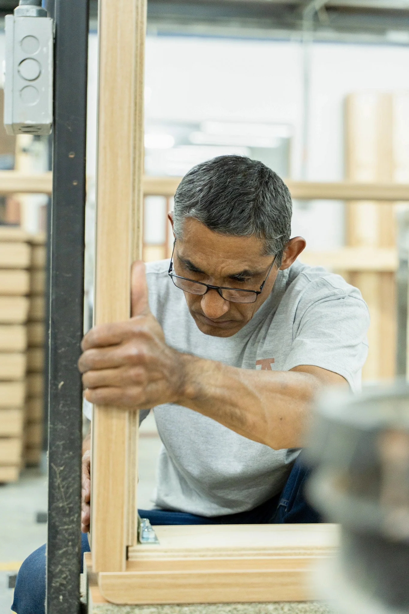 Hombre concentrado ajustando una estructura de madera en un taller.