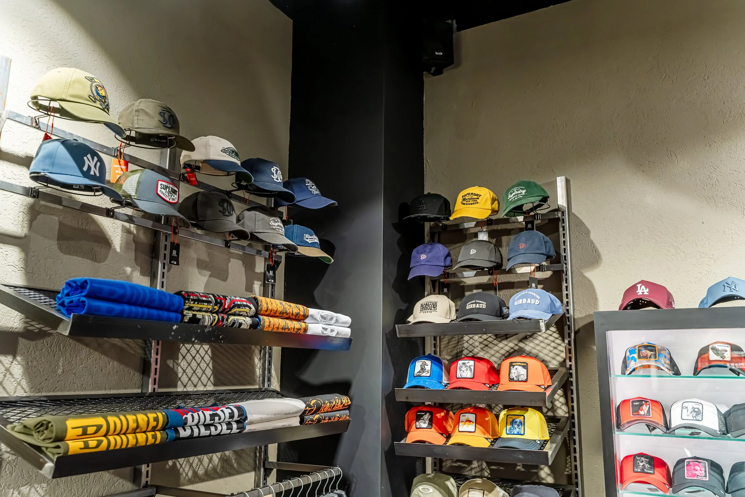 Estantería con gorras de diferentes colores y estilos, incluyendo logotipos de equipos deportivos, en una tienda.