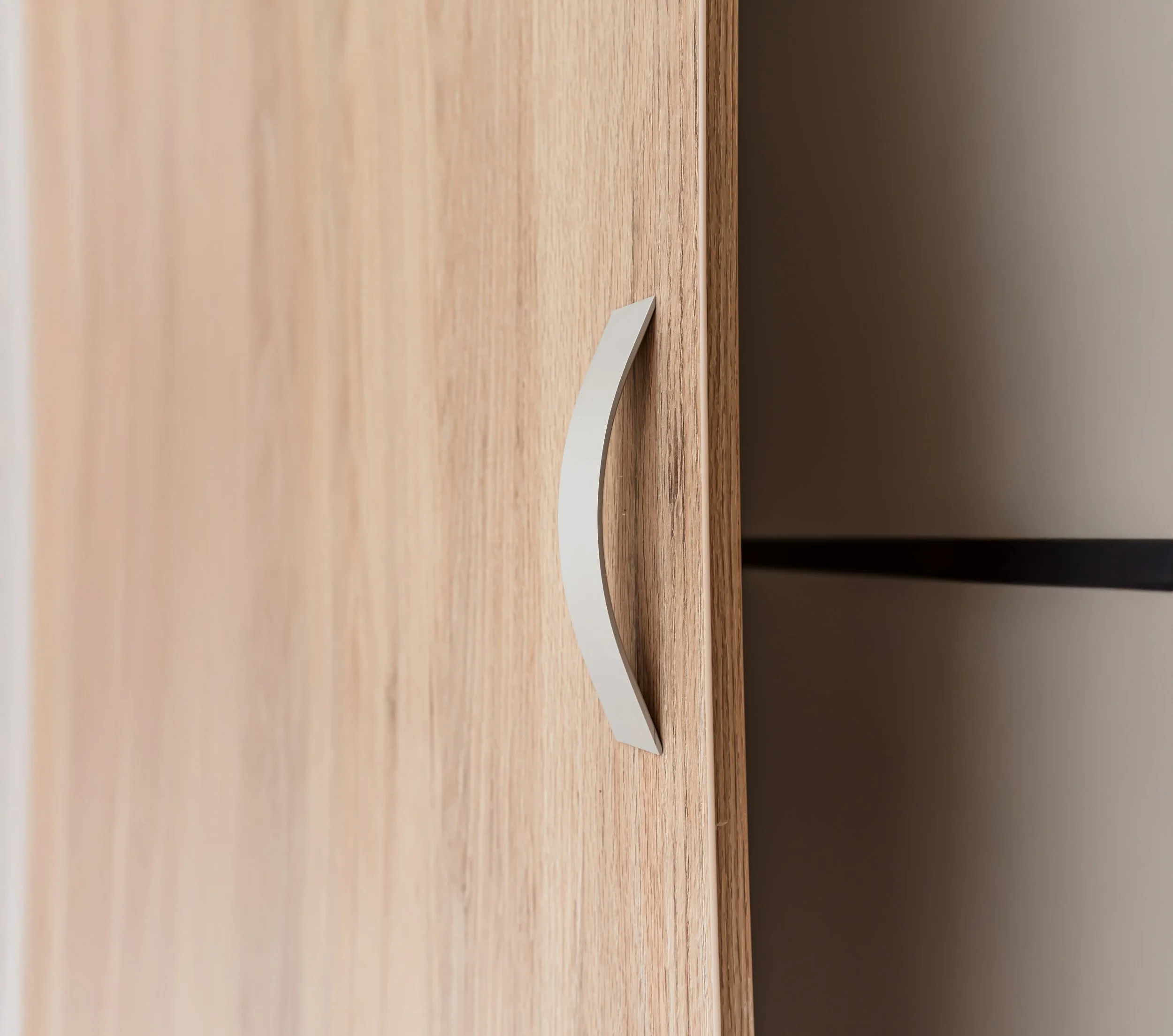 Vista lateral de un mesa de madera con una pequeña tarjeta blanca en la esquina. Fondo oscuro y pared beige.