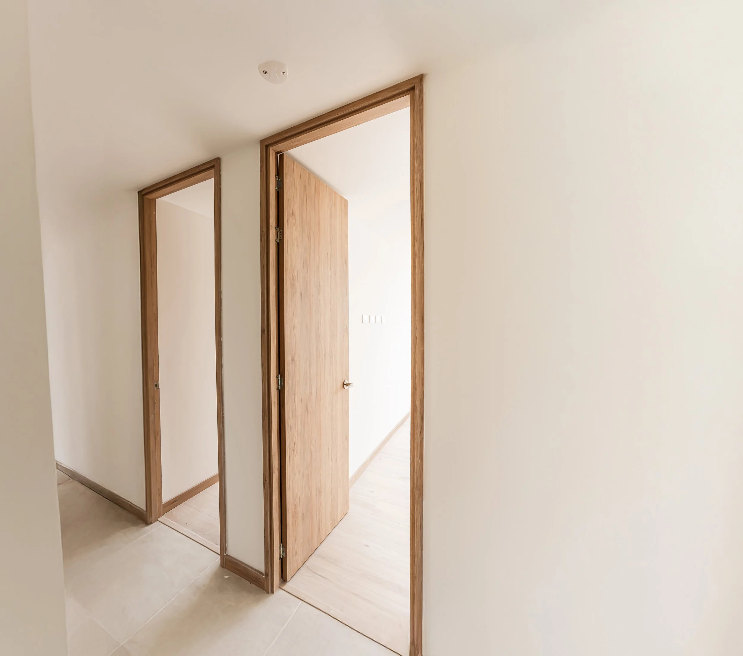 Puerta de madera enmarcada en una pared blanca, con una estructura de apertura que parece un armario o cabina, ubicada en un interior doméstico.