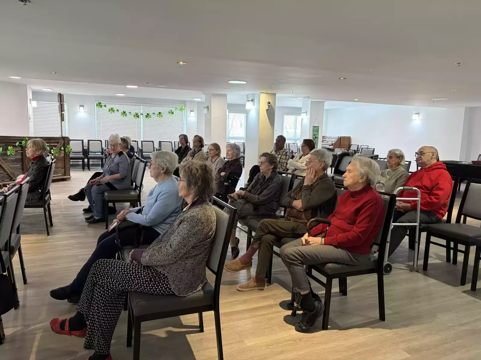groupe de personnes âgées assises dans une salle de conférence ou un auditorium, écoutant attentivement une présentation ou un discours.