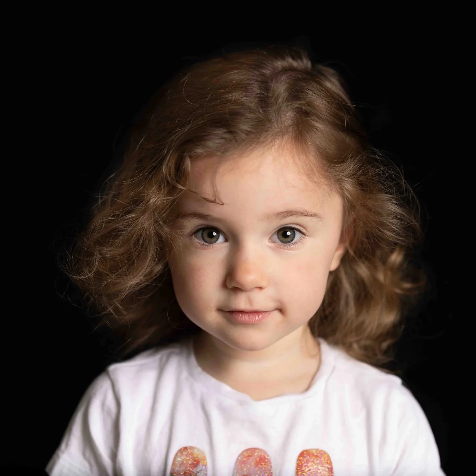 little girl with curly brown hair and brown eyes looking at the camera for her preschool photo