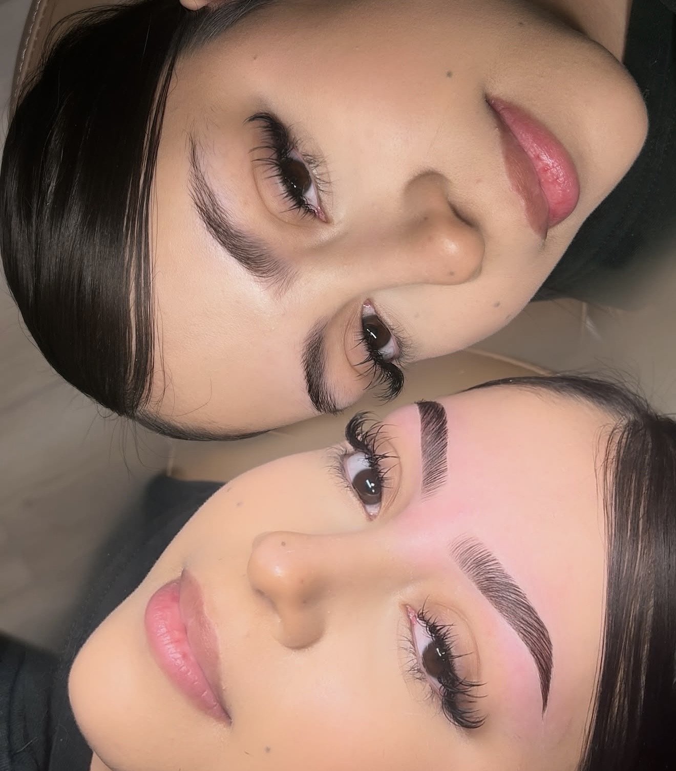 Close-up of two women with styled eyebrows and long eyelashes, lying down with their faces near each other, with their eyes open.